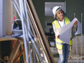 Woman in hardhat looking at blueprint