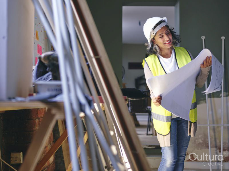 Woman in hardhat looking at blueprint