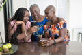 Smiling teenage girl with mother and grandmother looking at smart phone at table