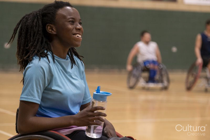 Teenage girl in wheelchair having water break during basketball game