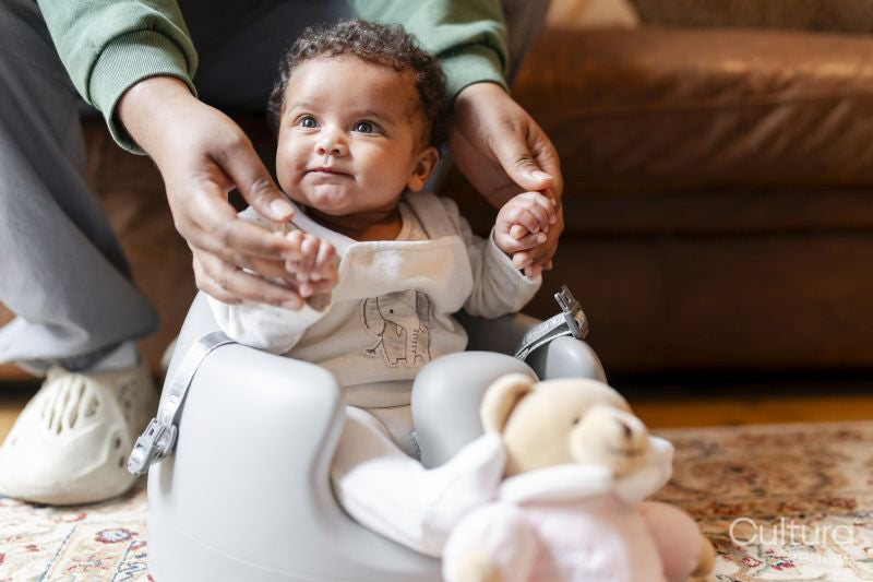 Father holding hands of baby daughter sitting