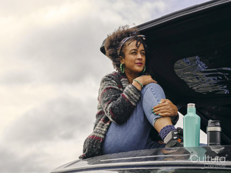 Woman sitting on roof of car