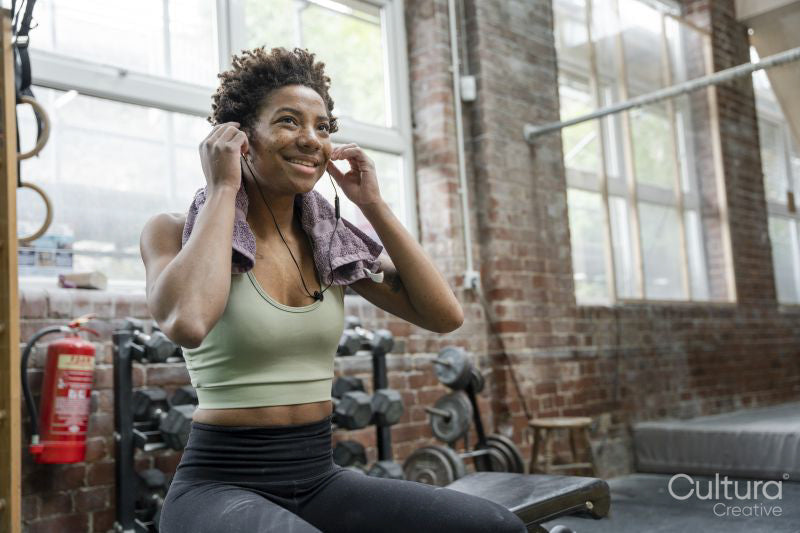 Woman putting earphones on during training on gym