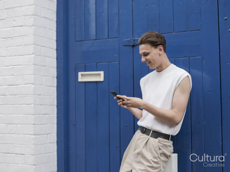 Young man standing against blue doors and using smart phone