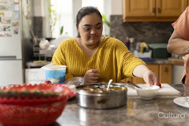 Young woman with down syndrome preparing food in kitchen