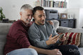 Smiling male couple taking selfie on sofa