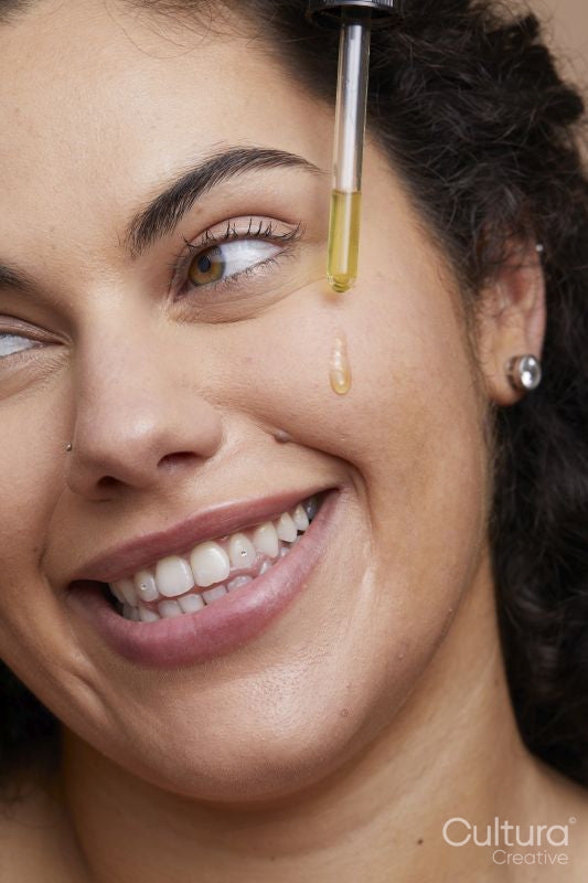 Close-up of young woman applying face serum