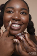Studio shot of smiling young woman applying lip moisturizer