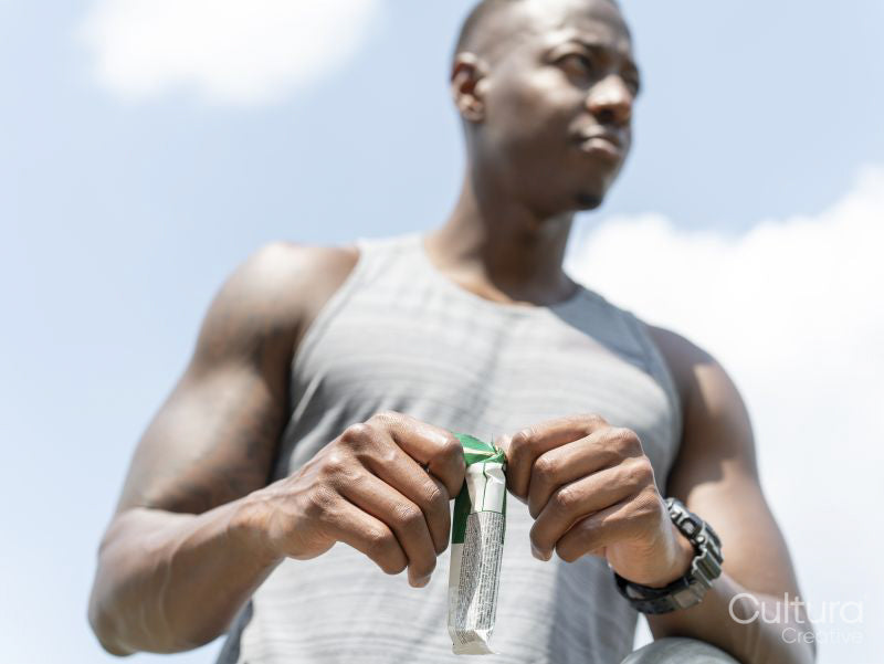 Man opening protein bar during workout