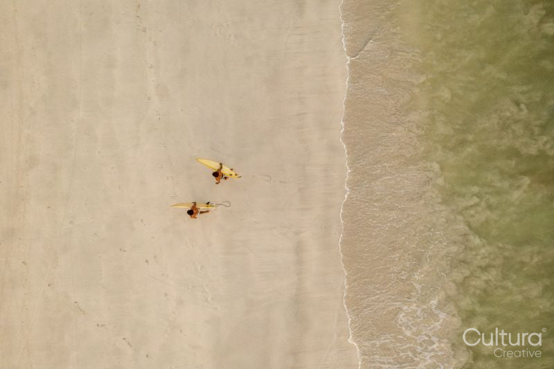 Indonesia, Lombok, Aerial view of men walking with surfboards on beach