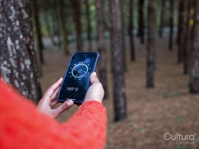 Female hiker using compass on smart phone