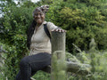 Portrait of smiling mature woman sitting on fence on hike