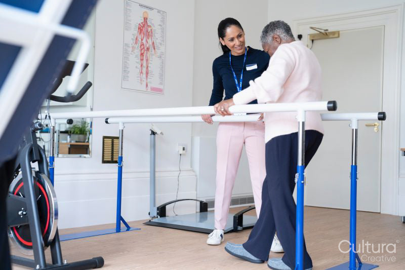 Smiling female therapist assisting senior woman walking on bars