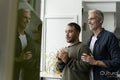 Mature male couple looking through window at home