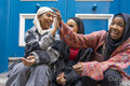 Three smiling women wearing hijabs sitting in front of blue door