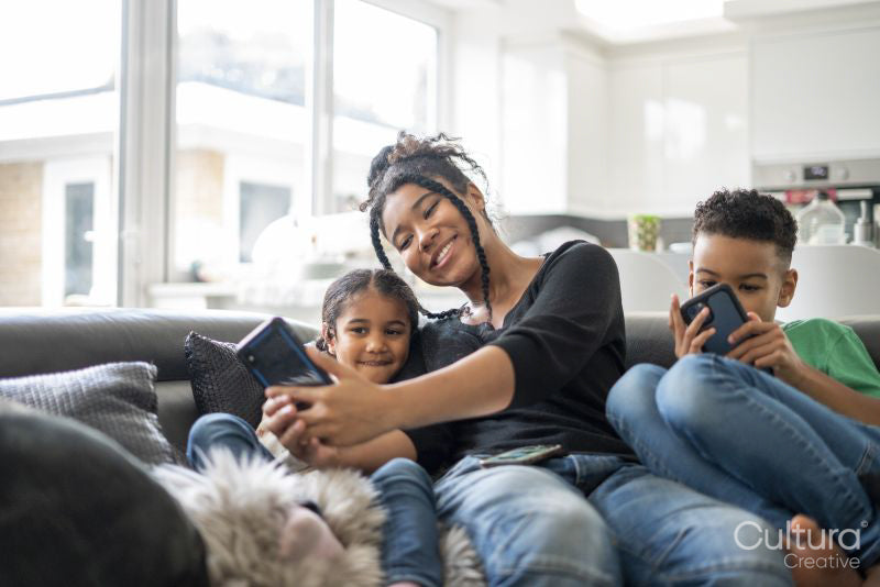 Two girls and boy sitting on sofa looking at smartphone