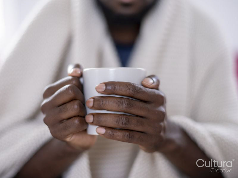 Close-up of person wrapped in blanket holding mug