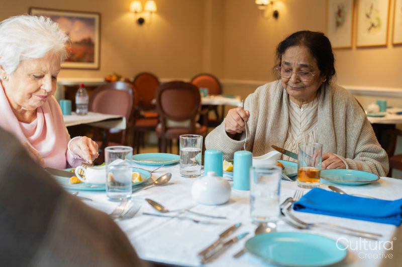 Two senior ladies dining at cafeteria in nursing home