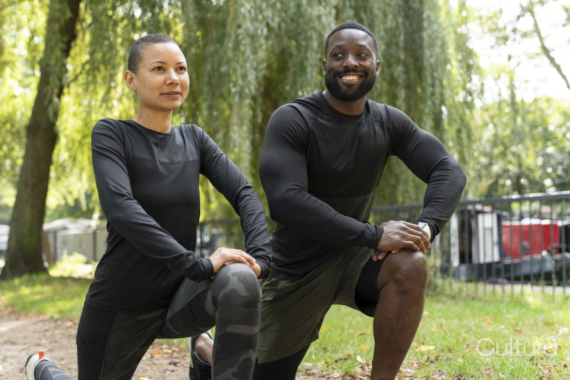 Smiling man and woman stretching legs in park
