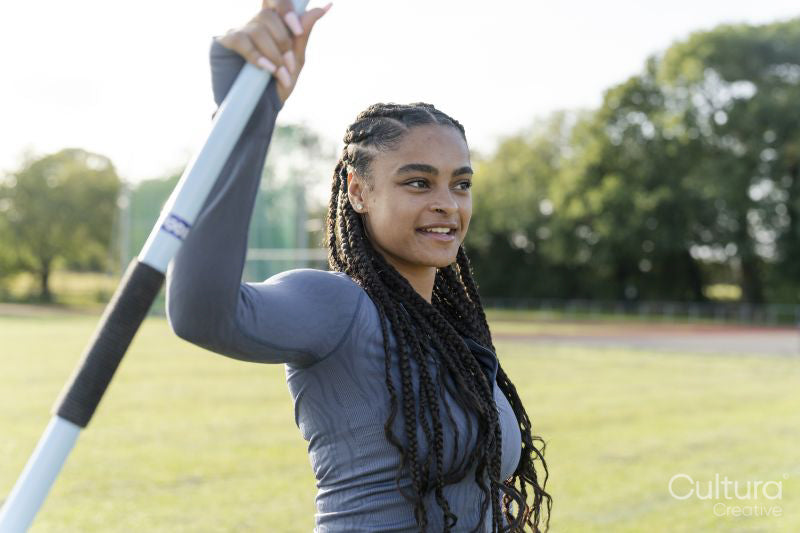 Portrait of confident female athlete holding javelin