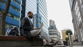Business man using laptop outside office building