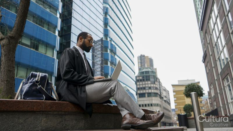 Business man using laptop outside office building