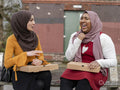 Two friends sitting on bench and laughing