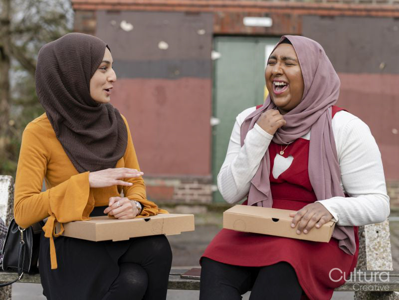 Two friends sitting on bench and laughing