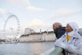 Female tourists in hijabs looking at London Eye over River Thames