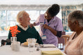 Nurse serving meal to senior people in nursing home