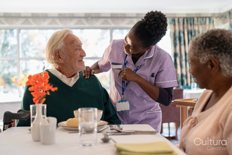 Nurse serving meal to senior people in nursing home