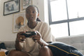 Serious young woman playing video games while sitting on sofa at home