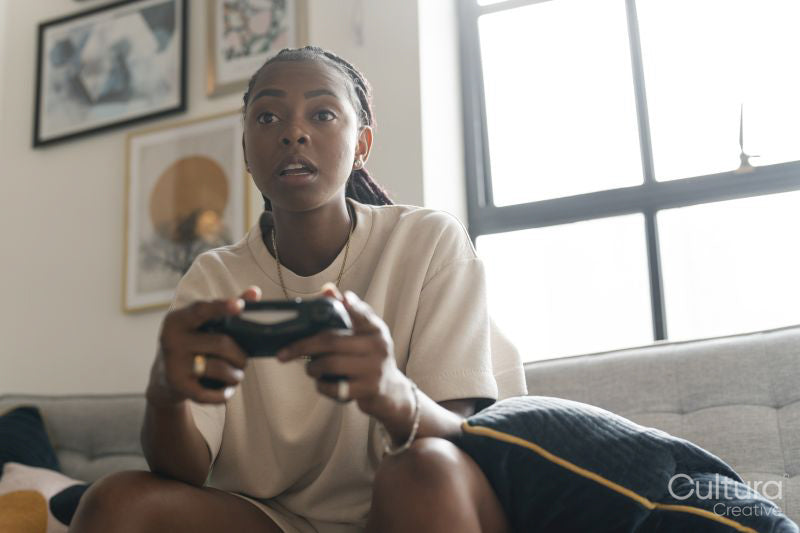 Serious young woman playing video games while sitting on sofa at home