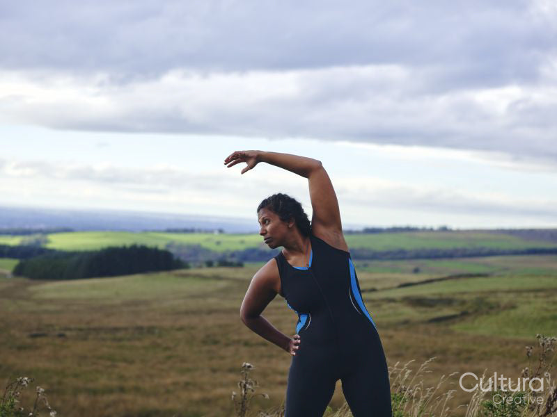 Female runner stretching in rural landscape