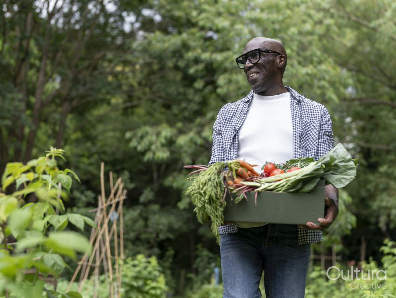 Smiling mature man holding vegetables from garden