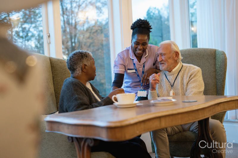 Smiling senior people and nurse talking at table in nursing home