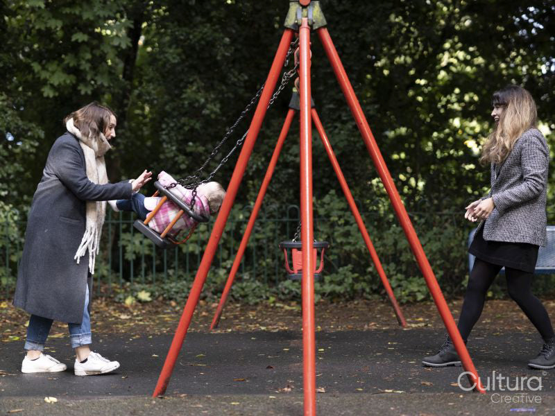 Female couple swinging baby in park