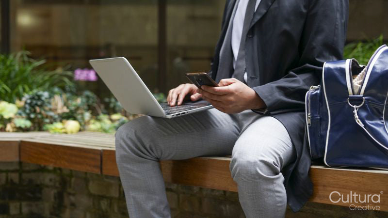 Midsection of business man using laptop and mobile phone