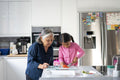 Senior woman with granddaughter chopping vegetables in kitchen