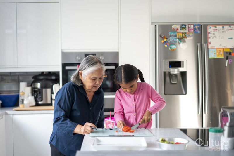 Senior woman with granddaughter chopping vegetables in kitchen