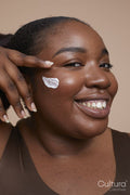 Studio portrait of smiling young woman applying face cream