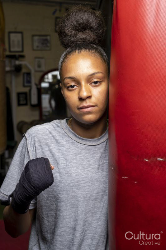 Young woman training on boxing bag, portrait