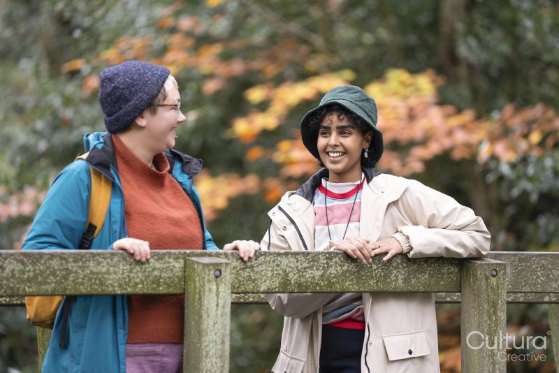 Female friends standing on bridge in forest