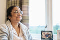 Senior lady wearing eyeglasses sitting next to window at nursing home