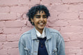 Smiling young woman standing against pink wall