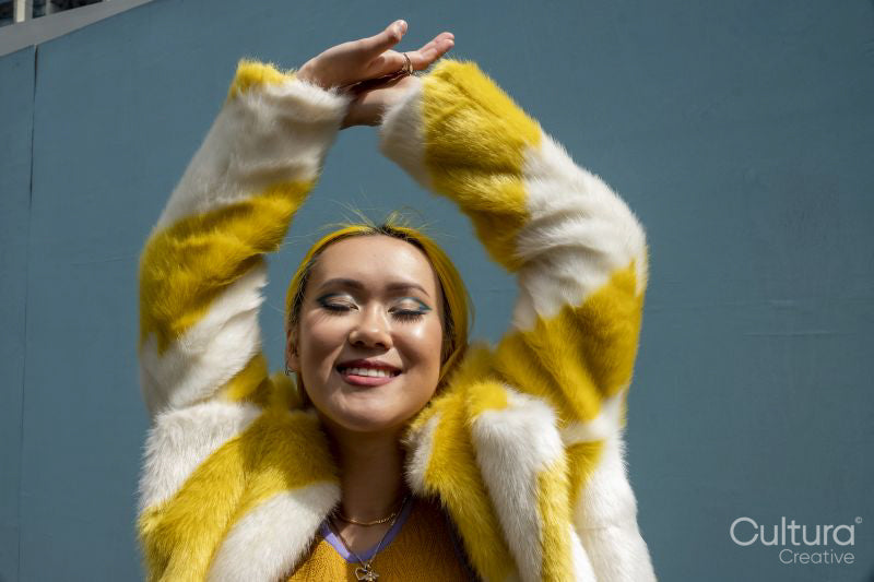 Young woman with yellow hair holding arms up
