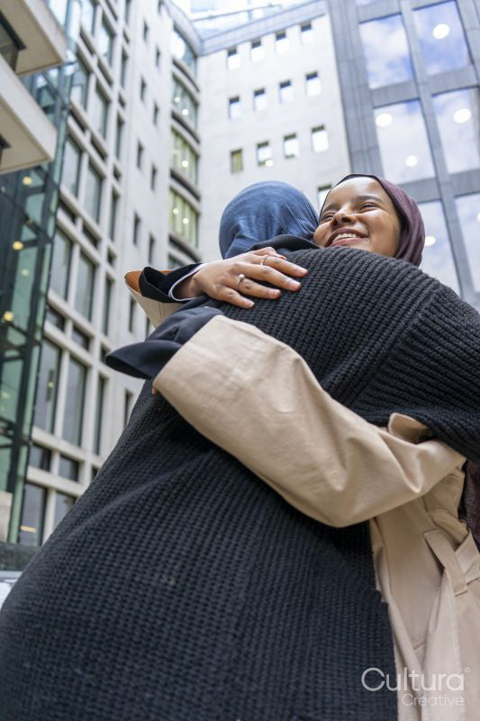 Two young women meeting in city
