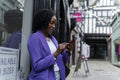 Smiling woman using smart phone while standing by building