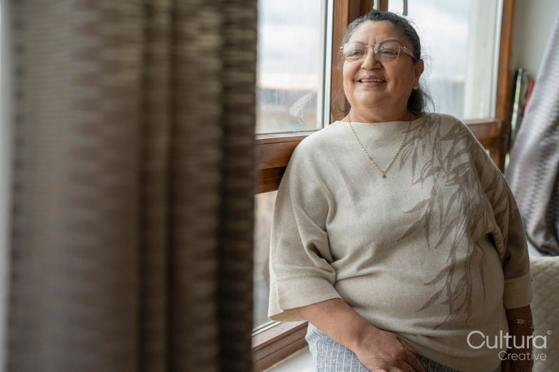 Smiling senior woman looking through window at home