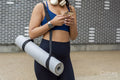 Woman with yoga mat using smart phone